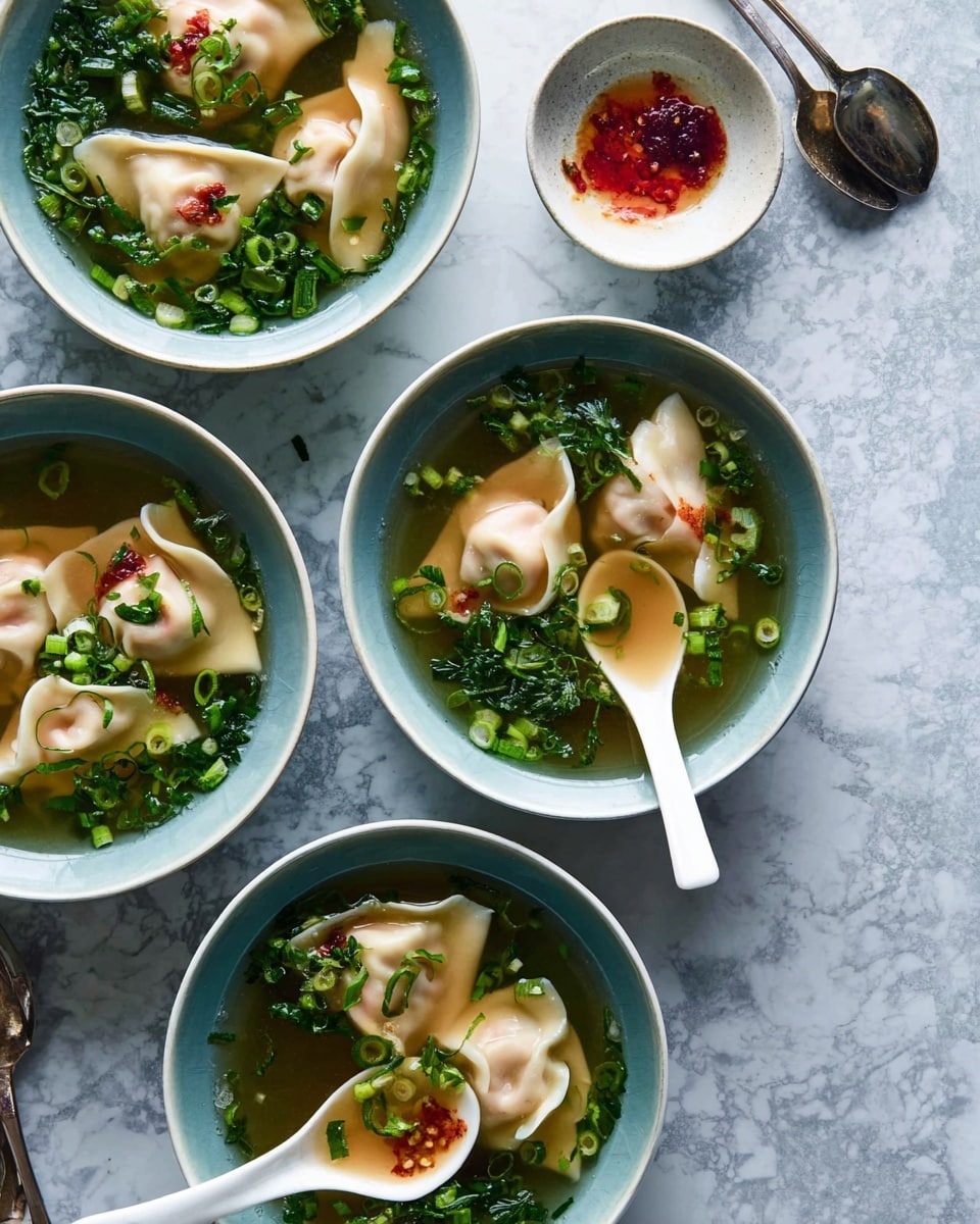 There are four white bowls filled with clear soup on a white marbled surface. Each bowl has three to four light beige dumplings with smooth, curved edges floating in the broth. Green chopped herbs and scallions are scattered on top of the dumplings and around them in the broth. Two bowls each have a white soup spoon resting inside, holding one dumpling with a bit of red sauce on it. A small white bowl with reddish sauce and a silver spoon is placed near the top right. The colors are soft and natural with a focus on the delicate dumplings and fresh green herbs. photo taken with an iphone --ar 4:5 --v 7
