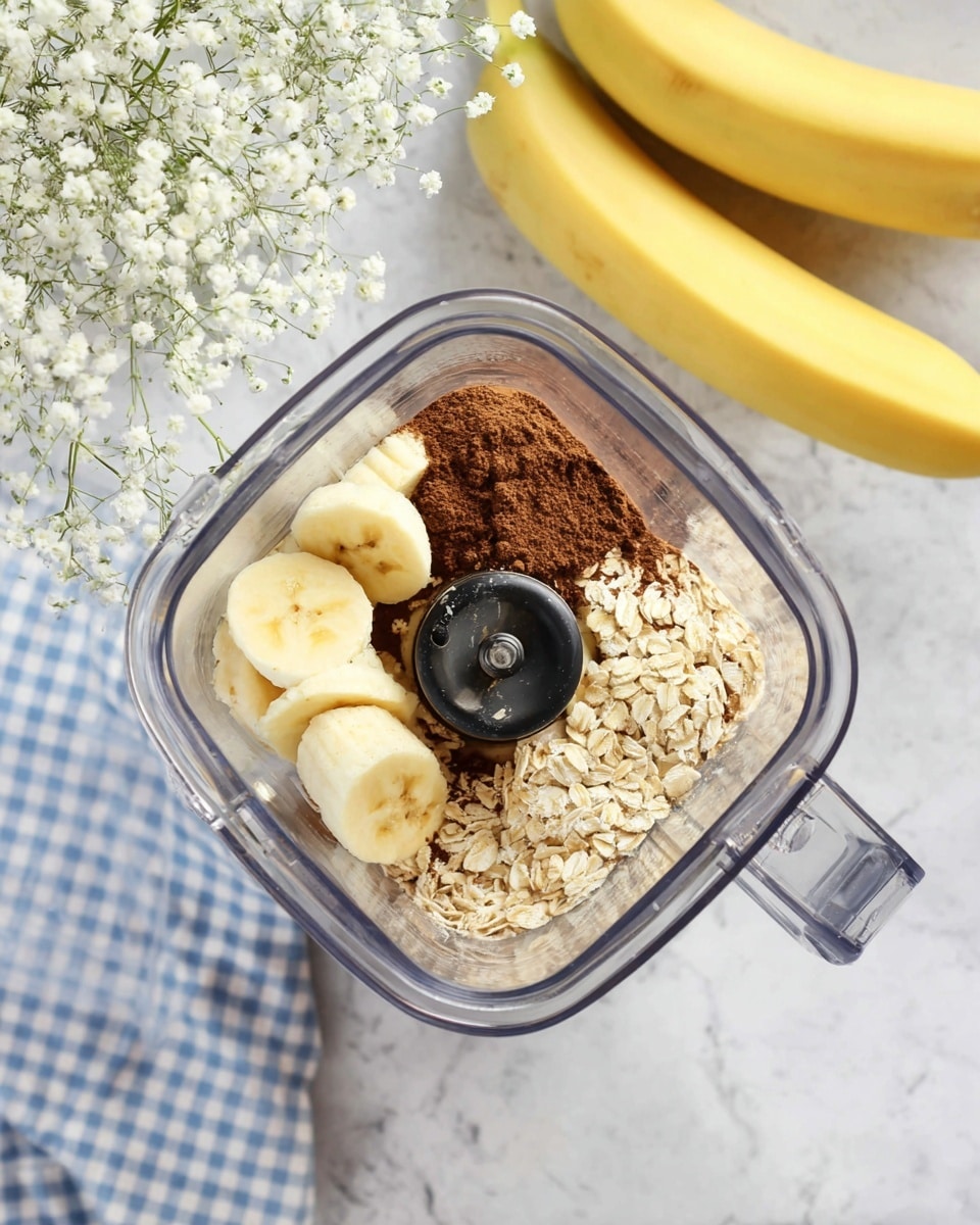 A clear blender container holds three distinct layers of ingredients: at the bottom, a rich dark brown powder covers part of the base; next to it, a layer of light beige rolled oats with coarse texture; on top, several thick banana slices arranged loosely around the blender blade. The blender is placed on a white marbled surface. In the upper part of the image, two bright yellow bananas with green tips rest on a blue and white checkered cloth. To the left, a glass vase with delicate white baby’s breath flowers adds a soft touch. Photo taken with an iphone --ar 4:5 --v 7