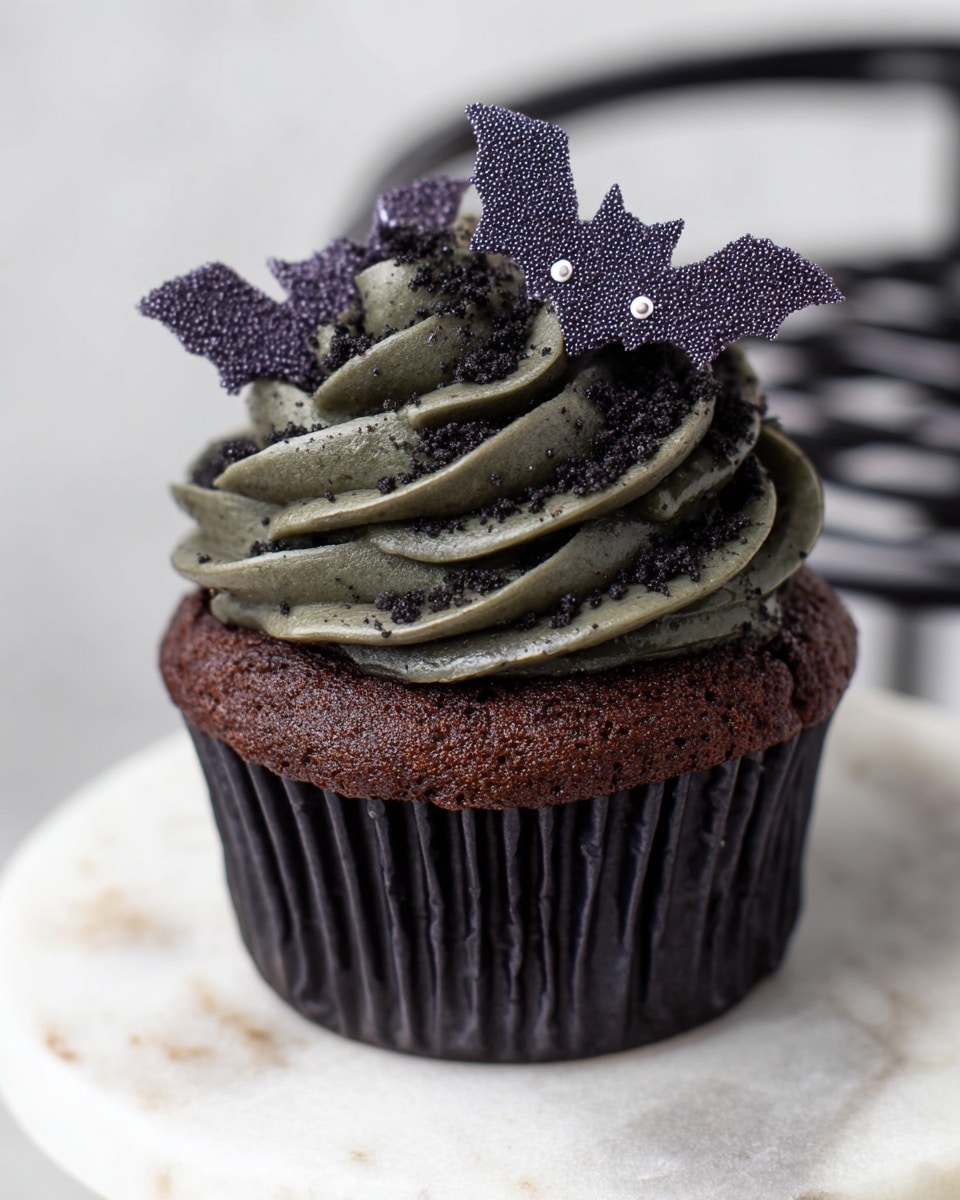 A dark chocolate cupcake sits in the center of a spider web shaped black wire stand. The cupcake has a deep brown cake base with a thick layer of dark grayish-black textured frosting swirled on top. Sitting on the frosting is a small purple bat-shaped edible decoration with white specks, adding a spooky touch. The background is a white marbled surface, creating a clean and bright contrast to the dark cupcake and stand. photo taken with an iphone --ar 4:5 --v 7