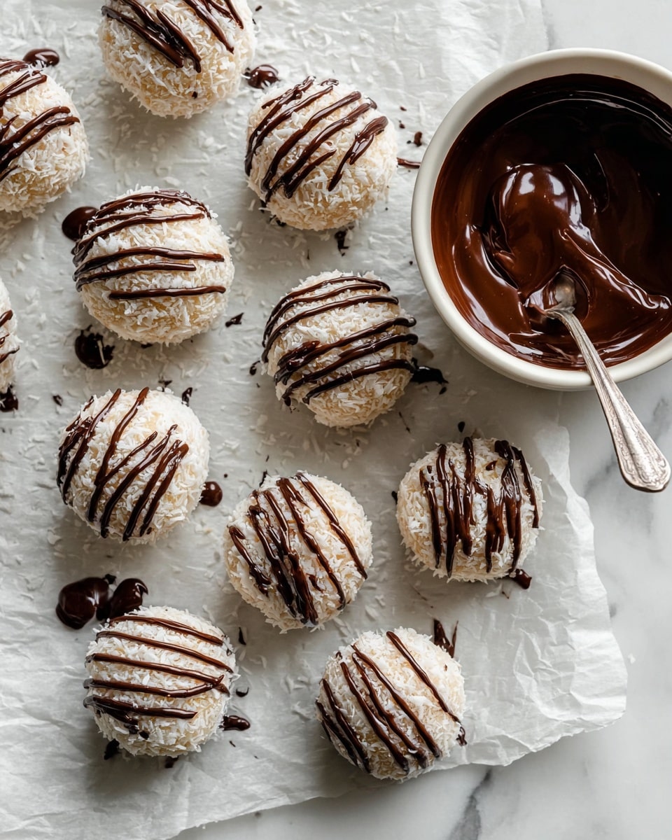 The image shows a group of round white coconut balls arranged on a sheet of parchment paper on a white marbled surface. Each coconut ball is covered in shredded coconut, giving them a rough texture, and is drizzled with smooth dark chocolate lines that run horizontally across their tops. In the top right corner, there is a white bowl filled with melted dark chocolate, with a spoon resting inside, coated in the chocolate. Some chocolate has spilled over the edge of the bowl, pooling slightly on the parchment. The scene has a clean, fresh look with a mix of textures from the flaky coconut and glossy chocolate, photo taken with an iphone --ar 4:5 --v 7