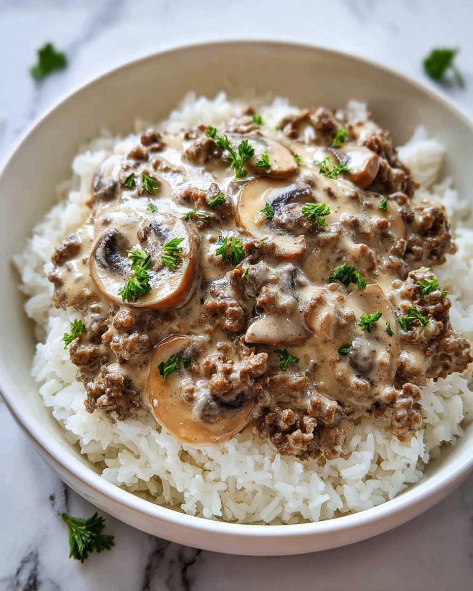 A white bowl filled with a base layer of white cooked rice with a soft, fluffy texture. On top, there is a thick layer of creamy mushroom sauce mixed with ground meat, showing brown sliced mushrooms and small bits of browned meat. The sauce has a smooth, slightly shiny texture with a light beige color mixed with darker brown spots from the mushrooms and meat. Small green parsley leaves are sprinkled on top for color contrast. The bowl is placed on a white marbled surface. Photo taken with an iphone --ar 4:5 --v 7