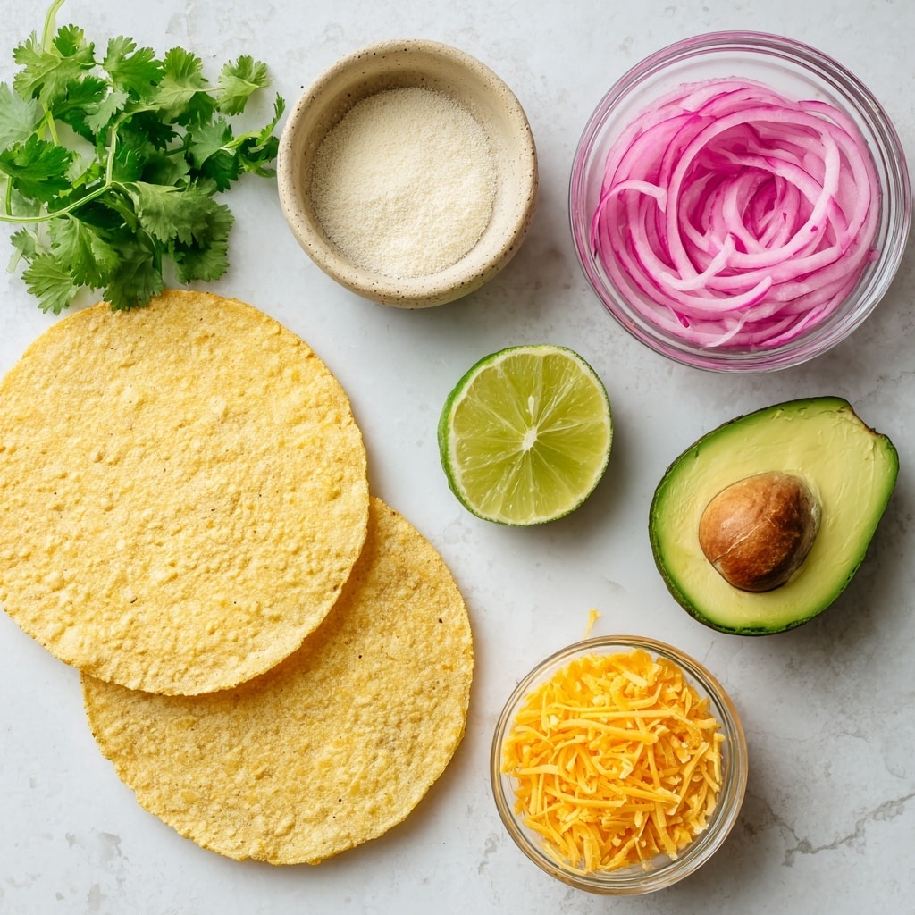 The image shows an overhead view of several fresh ingredients arranged on a white marbled surface. There are two crispy round tostada shells, light yellow with a grainy texture, positioned slightly overlapping at the bottom left. Above them to the left, a small bunch of bright green cilantro leaves rests directly on the surface. To the right of the cilantro is a small beige bowl containing white salt and pale yellow garlic powder side by side. Above the bowl is a lime wedge with a bright green rind and yellow-green flesh facing upward. Next to the lime is a small clear glass bowl filled with thin slices of pink pickled onion. On the right side of the image, two halves of a ripe avocado are placed with the darker bumpy outer skin on the outside and creamy green flesh visible; one half still holds a brown seed in the center. A small clear glass bowl of finely shredded bright orange cheese sits at the bottom right corner. All elements are spaced apart neatly, with clear labels indicating each ingredient. Photo taken with an iphone --ar 4:5 --v 7