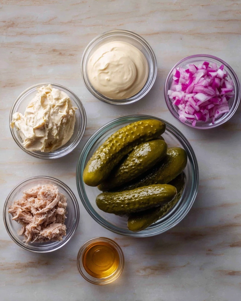 The image shows five small bowls arranged on a white marbled surface, each containing a different ingredient. In the center is a larger clear bowl filled with five whole pickles, dark green with a shiny, wet texture. To the top left is a small clear bowl with creamy, off-white mayo that looks thick and smooth. Below it, another small clear bowl holds light brown chunks of tuna with a soft, slightly flaky look. To the top right, a small clear bowl contains finely chopped red onion pieces, bright purple and white with a fresh, crisp texture. Finally, at the bottom right, a very small clear bowl holds a small amount of golden honey with a shiny, liquid surface. photo taken with an iphone --ar 4:5 --v 7