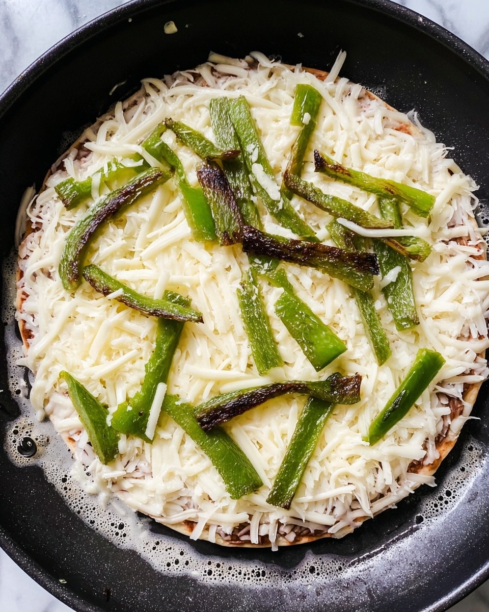 A close-up image of a small round pizza cooking in a black pan, showing three distinct layers. The bottom layer is a thin, light brown pizza crust slightly bubbly at the edges. On top of the crust, there is a thick even layer of shredded white cheese covering the whole surface. Scattered on the cheese are uneven strips of cooked green bell pepper, some darker and charred, arranged randomly. The edges of the crust are visible around the toppings, and the pan's surface has small bubbles of oil or melted cheese around the pizza. The background is a white marbled texture. photo taken with an iphone --ar 4:5 --v 7