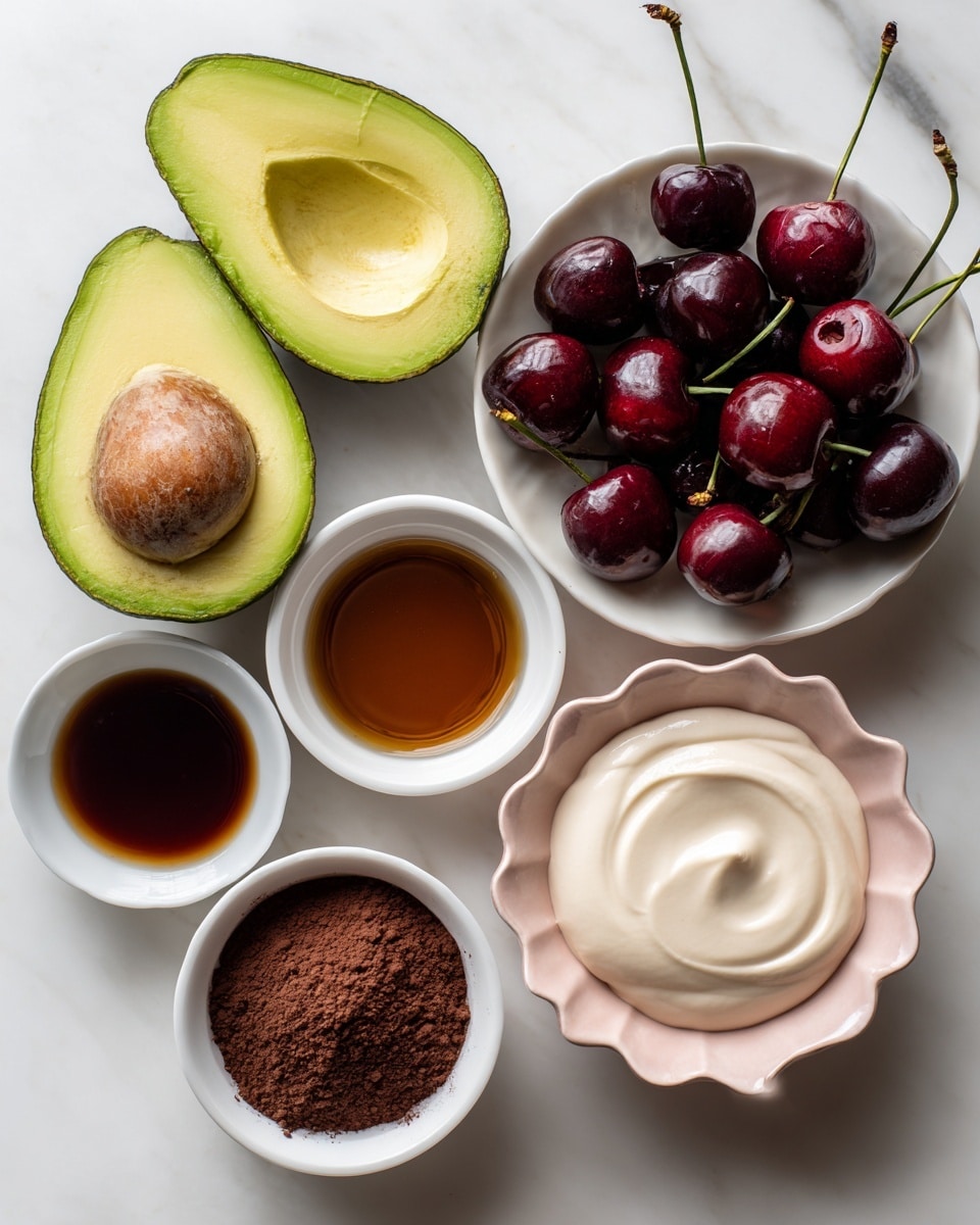 The image shows a top view of several food ingredients placed on a white marbled surface. On the left, there are two halves of a ripe avocado with one half still containing the brown seed, showing a smooth, green inside with a darker green outer skin. To the right, there is a bowl filled with dark red cherries with stems, creating a shiny, rich texture. Below the avocado, a small white bowl holds a dark brown liquid labeled maple syrup, and next to it, another small white bowl is filled with dark brown cocoa powder that has a fine, powdery texture. Below these, a white bowl contains melted dark chocolate with a glossy surface. To the right, there is a white bowl with creamy, smooth dairy-free whipping cream in off-white color, and next to it, a white bowl with a pink scalloped edge holds a beige liquid labeled dairy-free milk. All the bowls and ingredients are neatly arranged, showing contrast in colors and textures on the clean white marbled surface photo taken with an iphone --ar 4:5 --v 7