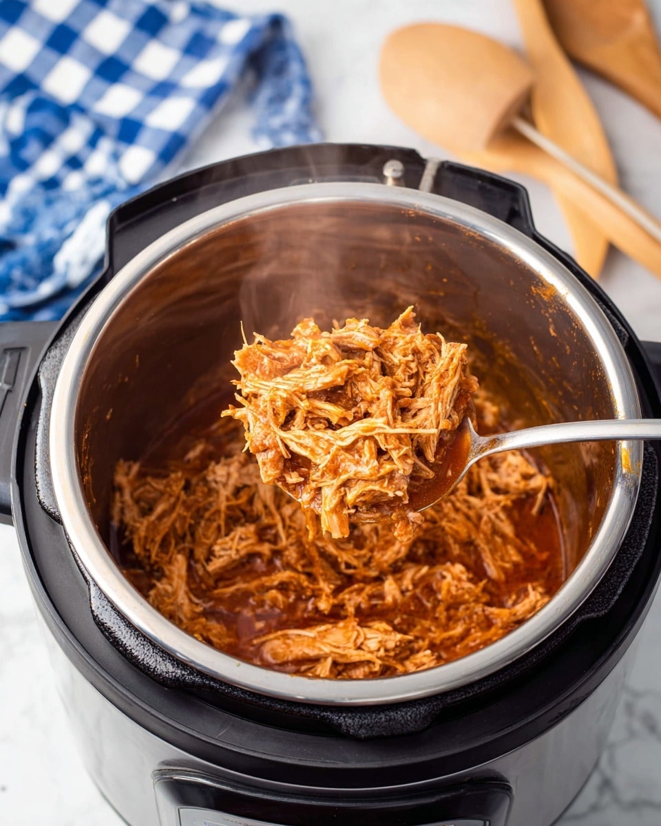 The image shows an open black electric pressure cooker with a shiny silver inner pot filled with shredded meat in a rich reddish-brown sauce. A silver spoon lifts a large portion of the meat up from the pot, showing the moist, tender texture of the shredded meat. Steam rises from the meat, giving a fresh cooked feel. The cooker is on a white marbled surface, with a blue and white checkered cloth and a wooden spoon blurred in the background. Photo taken with an iphone --ar 4:5 --v 7