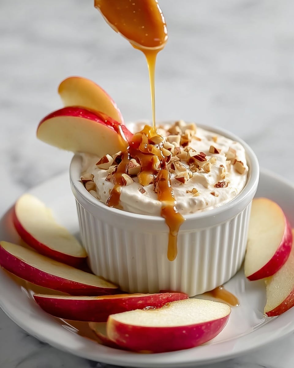 A white ribbed ramekin filled with creamy white yogurt forms the base layer, topped with scattered light brown walnut pieces in the center. A thin swirl of golden caramel sauce circles the walnuts on top of the yogurt. The ramekin sits on a pale yellow plate with thin apple slices fanned out neatly along one side. A soft brown cloth is draped casually beside the plate, and the background is a white marbled surface. photo taken with an iphone --ar 4:5 --v 7