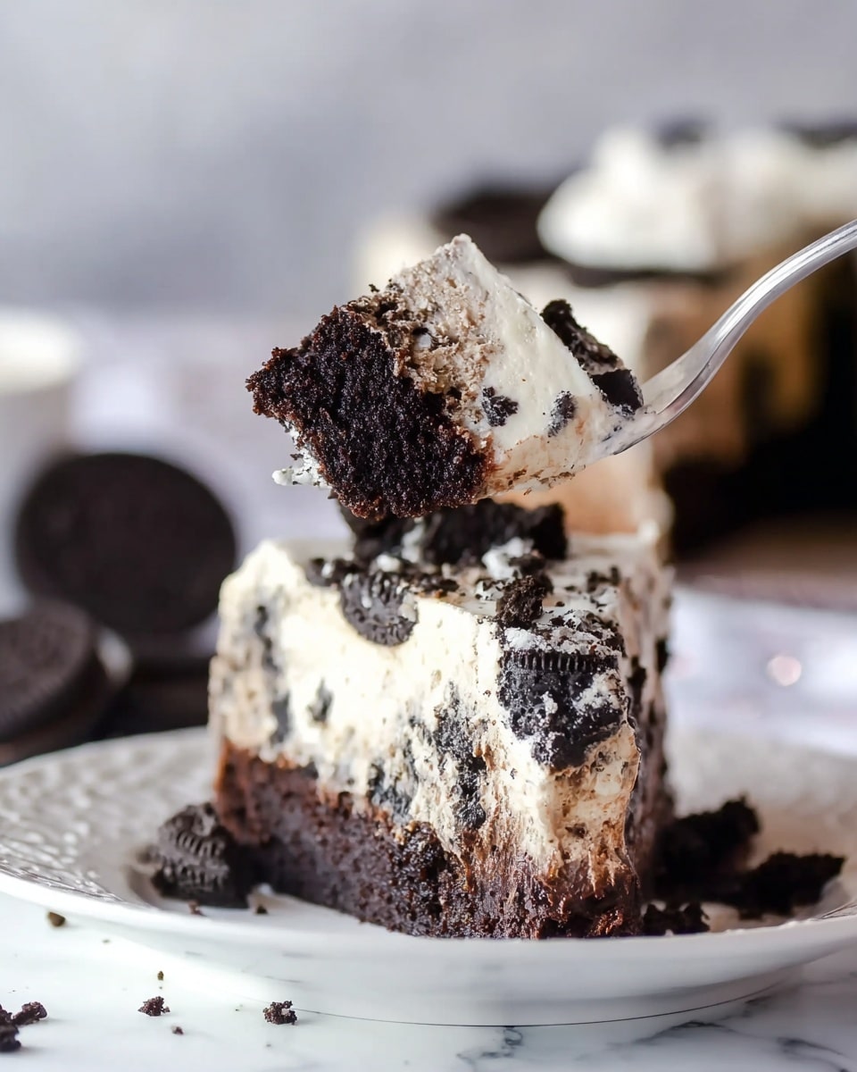 A thick slice of dessert with three visible layers is shown being lifted on a fork. The bottom layer is dark, dense chocolate cake with a rich texture. Above that is a creamy white layer speckled with large black cookie pieces, adding a rough, crumbly look. The top layer is smooth white cream with more cookie bits scattered around. The slice is on a white plate with a delicate pattern, placed on a white marbled surface. The background is softly blurred showing the rest of the dessert and some whole cookies. Photo taken with an iphone --ar 4:5 --v 7