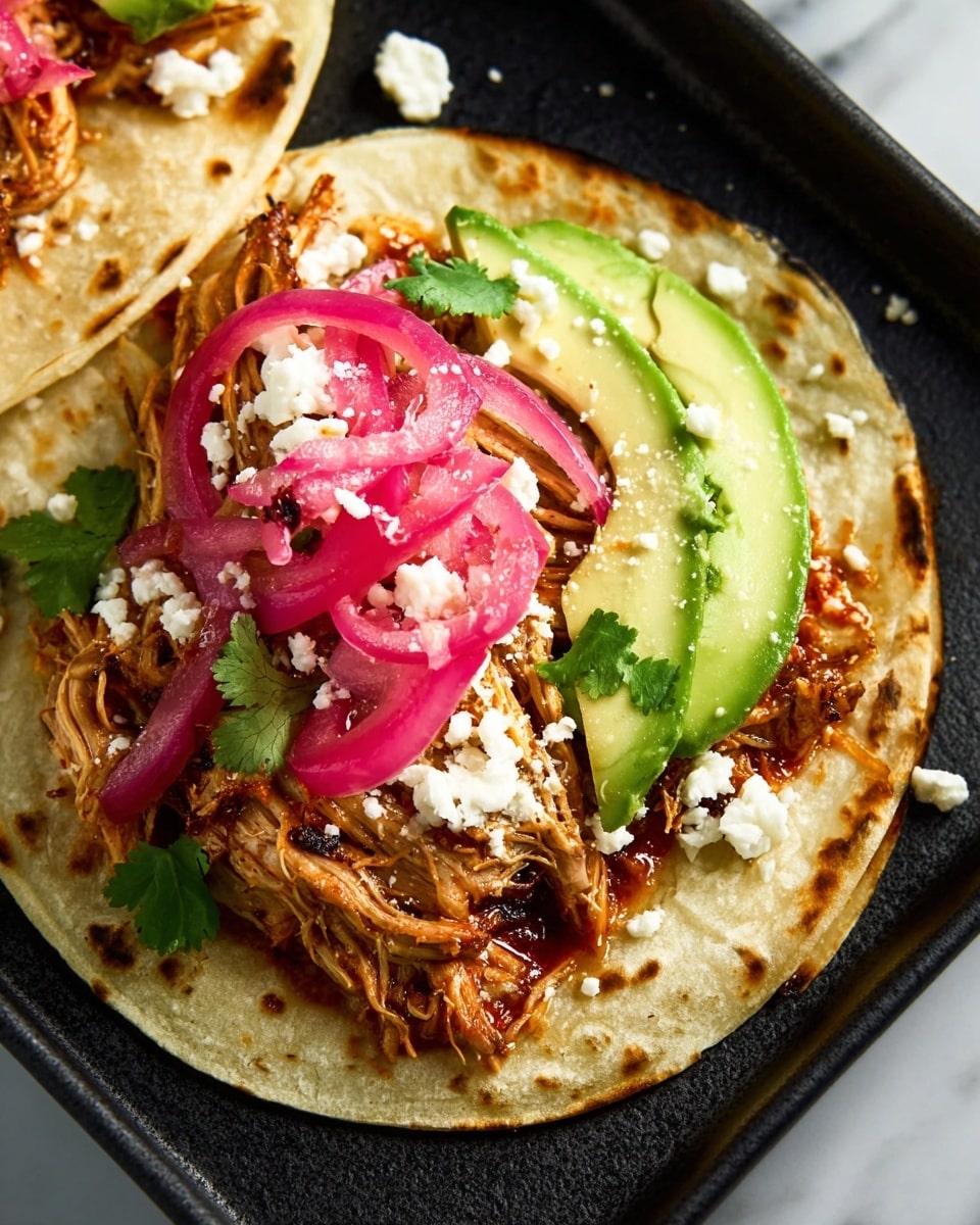 The image shows a white plate filled with shredded meat covered in a rich brown sauce, giving it a moist and slightly glossy texture. The meat is piled high in the center of the plate, showing thin strands and fibers throughout. On the top center of the meat sits a small bunch of fresh green cilantro leaves for garnish. Around the plate, on a white marbled surface, there are some whole red chili peppers and lime halves, adding bright red and green colors to the scene. A grey and white striped cloth is partially visible under the plate. photo taken with an iphone --ar 4:5 --v 7