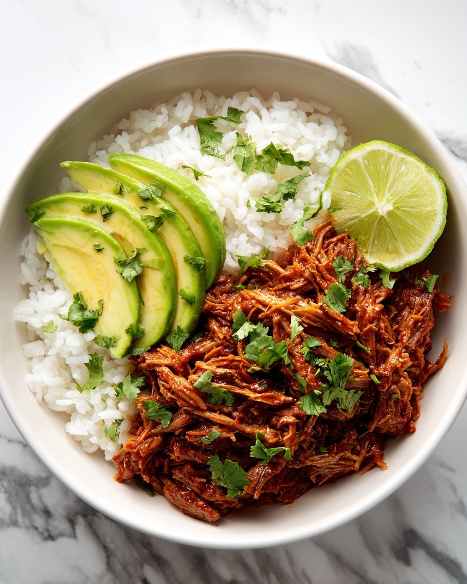 The image shows a white bowl filled with three layers: at the bottom is soft white rice, in the middle is shredded cooked meat coated with a reddish sauce, and on top there are fresh green cilantro leaves. On one side of the bowl, there are slices of bright green avocado, and on another side, lime wedges. The bowl is placed on a white marbled surface. In the background, there is half an avocado and one lime, along with a silver spoon with a green handle. The photo is taken with an iphone --ar 4:5 --v 7