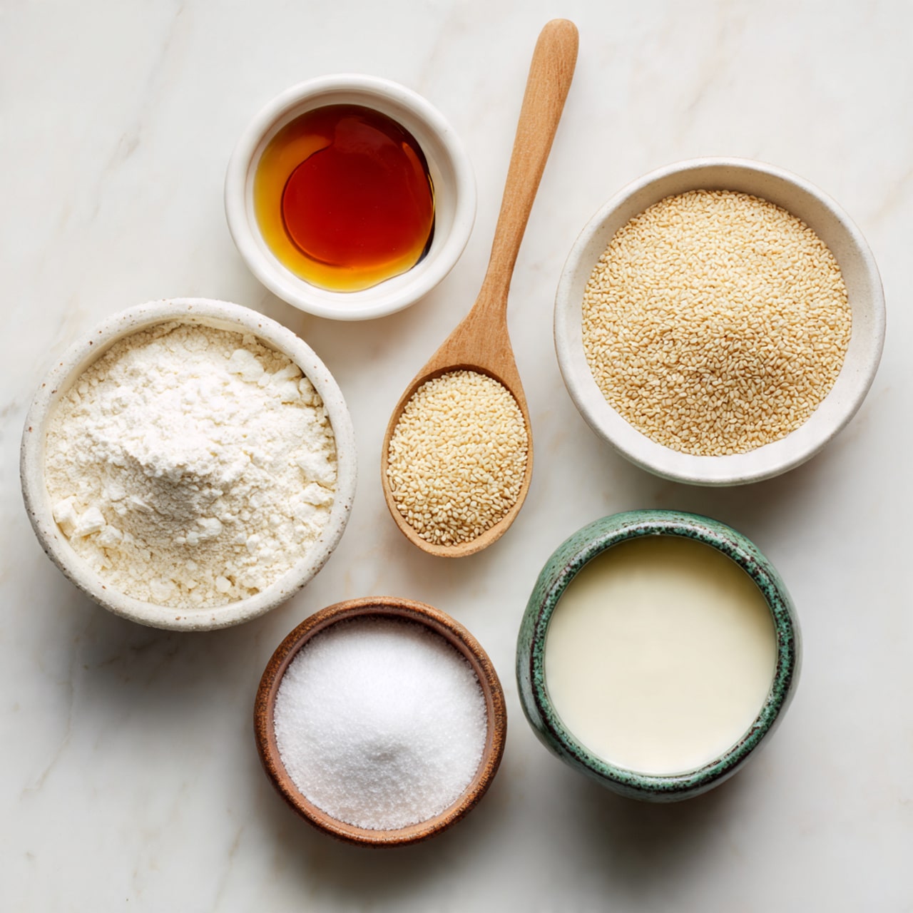 The image shows six ingredients arranged on a white marbled surface. There is a white small bowl at the top left holding amber-colored vanilla extract. To its right, a wooden spoon holds beige instant dry yeast. Below the spoon is a white bowl filled with light tan sesame seeds. At the bottom right, a white bowl with a green rim contains pale yellow milk. Centered on the left side, a white bowl filled with white flour is visible. Below the flour bowl to the left, a small wooden spoon holds white baking powder. Finally, at the bottom center, a white bowl with a brown rim is filled with fine white sugar. Each bowl and spoon is evenly spaced, creating a clean and organized look. Photo taken with an iphone --ar 4:5 --v 7