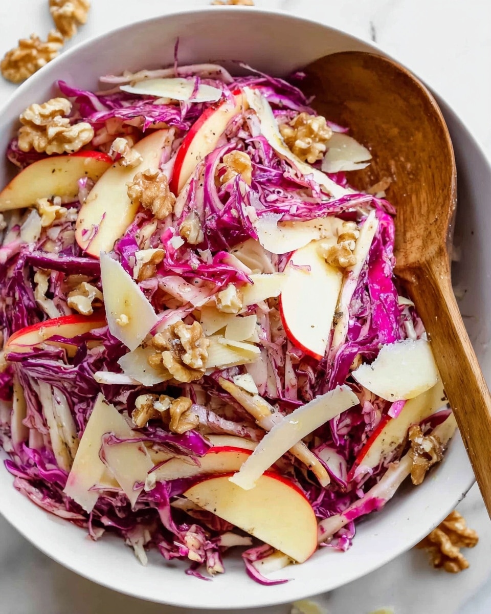 The image shows a white bowl filled with a colorful salad inside. The salad has three main layers: thinly sliced red cabbage with a purple color and a slightly crunchy texture, thin slices of apple with red skin and white inside, and pieces of light brown walnuts scattered on top. There are also small thin white shavings of a hard cheese spread across the salad. A wooden spoon is placed inside the bowl lifting some of the salad. The bowl is set on a white marbled surface with small pieces of walnuts spilled around it. Photo taken with an iphone --ar 4:5 --v 7