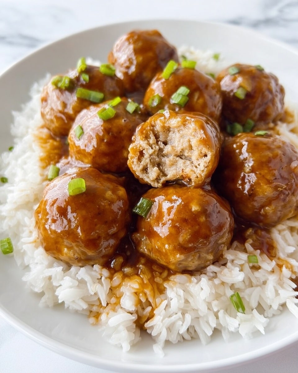 A white plate holds a serving of cooked white rice topped with six brown glazed meatballs. The meatballs have a shiny, thick sauce covering them, with little green onion pieces sprinkled on top. One meatball is cut open, showing a light brown texture inside. The rice grains appear fluffy and slightly separate from each other. The plate sits on a white marbled surface. Photo taken with an iphone --ar 4:5 --v 7