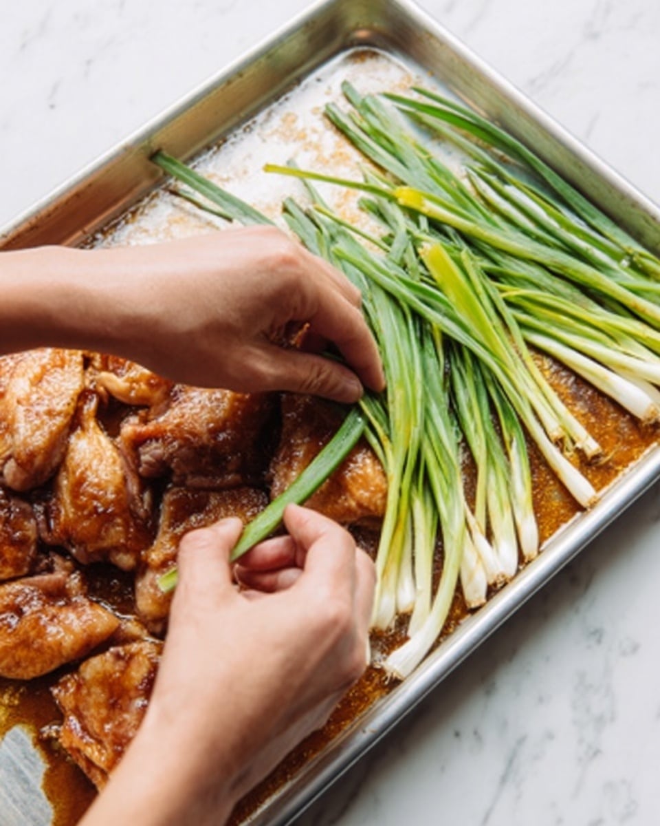 The image shows pieces of seasoned chicken skin on a metal tray with a brown sauce underneath. A woman's hands are placing fresh green onions with long stalks on the right side of the tray. The chicken's surface is shiny and slightly moist, and the green onions are bright and crisp. The tray is set on a white marbled surface. Photo taken with an iphone --ar 4:5 --v 7