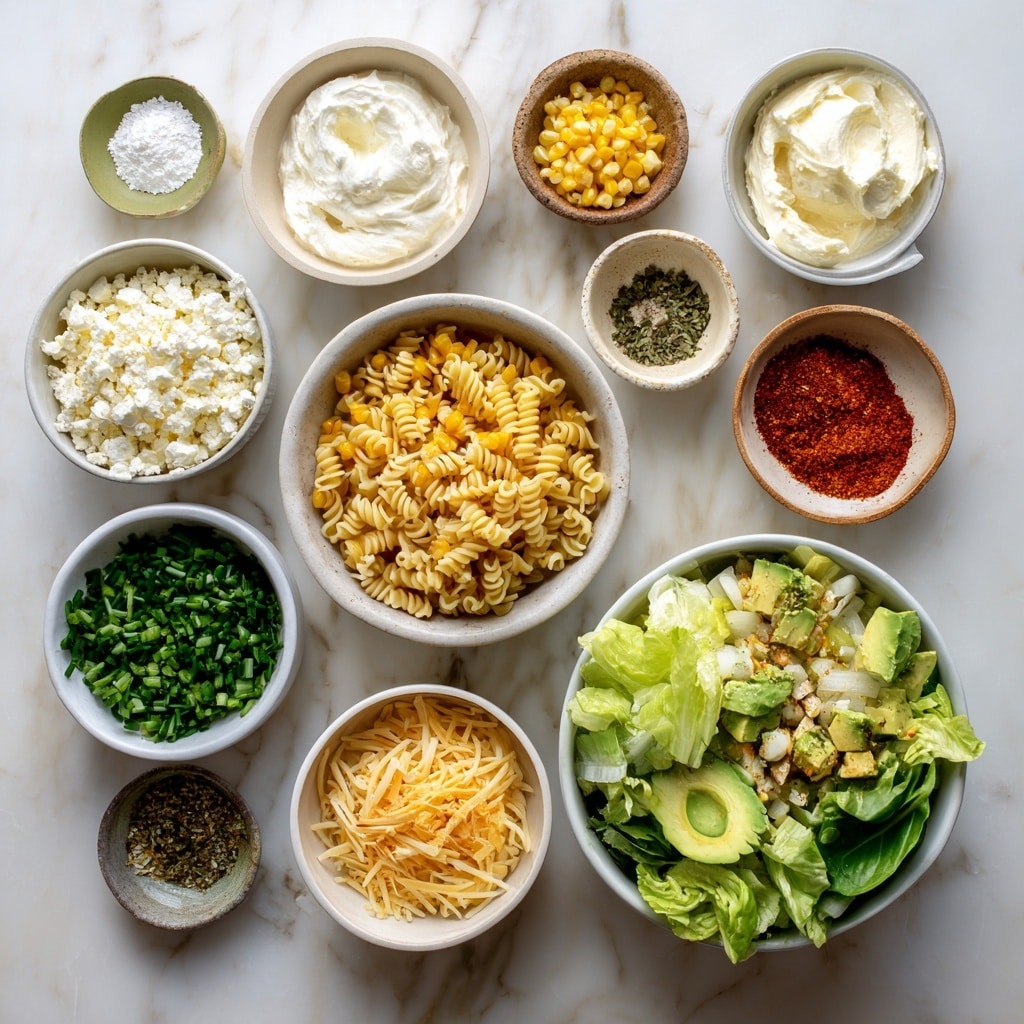 A white bowl filled with spiral pasta layered at the bottom, topped with bright yellow grilled corn pieces that have dark char marks, scattered dollops of white crumbly cheese, and fresh green basil leaves spread across. There are also chunks of green avocado nestled among the pasta, with a light dusting of reddish seasoning over the top. The bowl sits on a white marbled surface with lime wedges and basil leaves placed nearby. Photo taken with an iphone --ar 4:5 --v 7