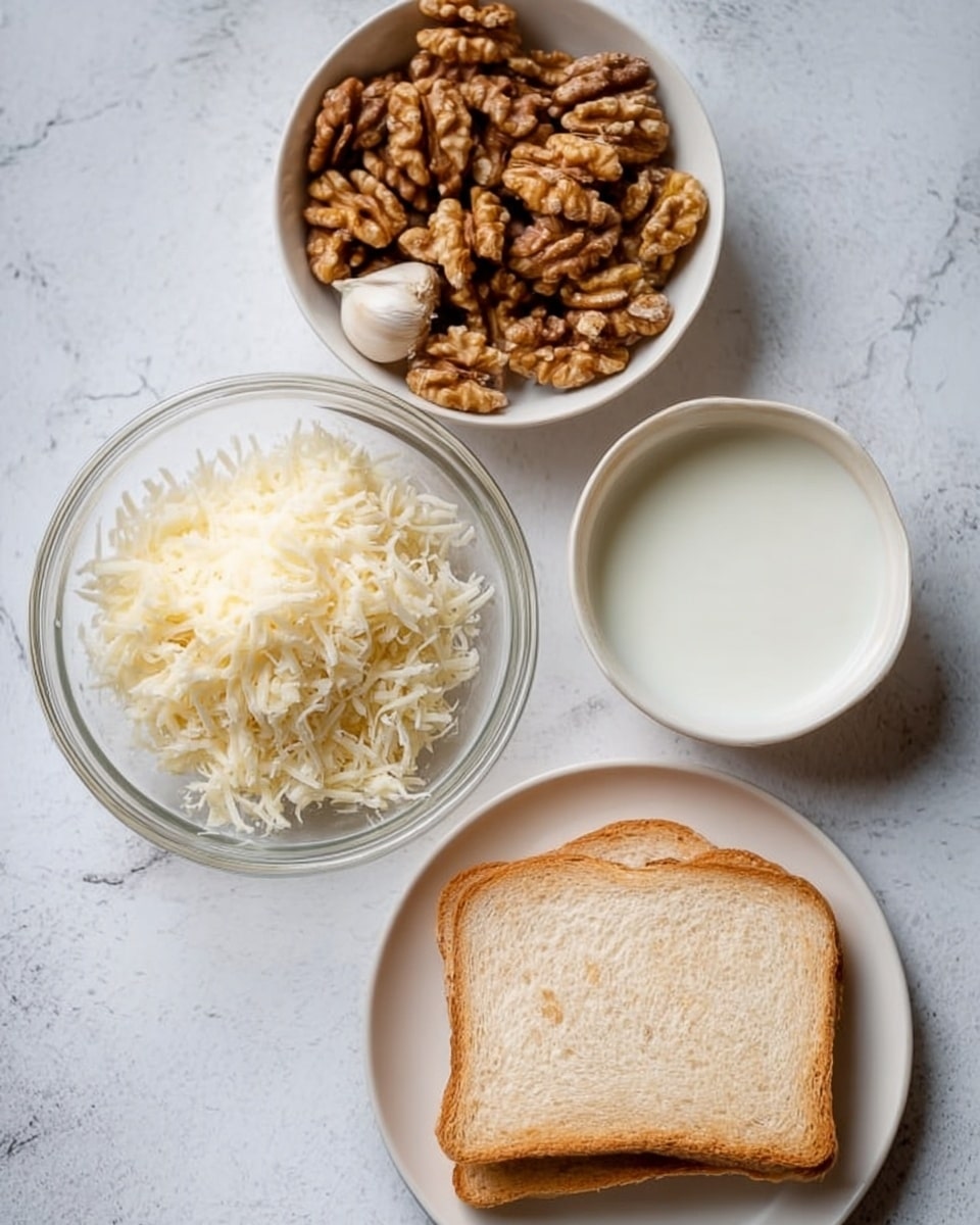 The image shows four bowls and plates arranged on a white marbled surface. At the top, there is a bowl filled with light brown shelled walnuts with one white garlic clove nestled among them. To the left, there is a clear glass bowl containing a large amount of fine, shredded white cheese. On the right side, a small white bowl holds a smooth, white liquid, likely milk or cream. At the bottom, a plain white plate holds a single slice of light brown bread with a soft texture. The items are displayed in a simple and clean way, with no other objects in the scene. Photo taken with an iphone --ar 4:5 --v 7