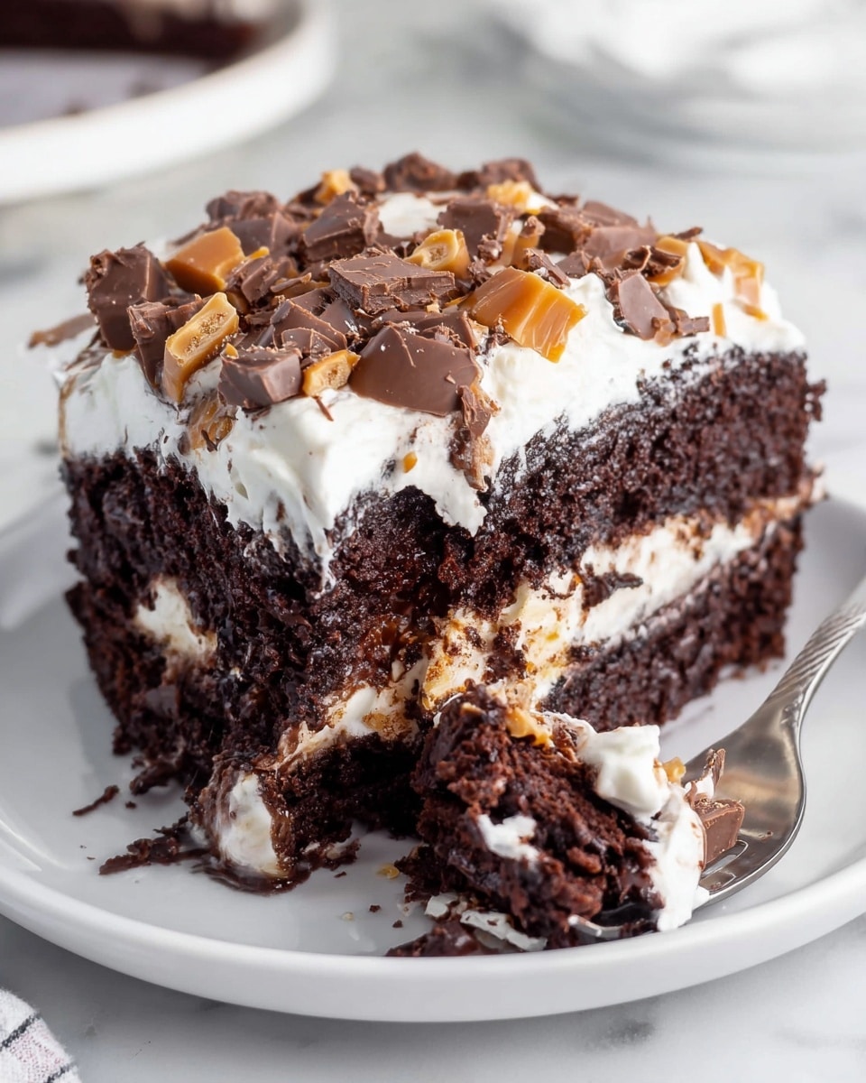 A slice of dark brown chocolate cake with two thick layers and some creamy white filling in the middle sits on a white round plate. The top layer of the cake is covered with a thick, fluffy white frosting. On top of the frosting, there are many small chunks and pieces of chocolate and caramel candy, adding texture and color contrast. A silver fork is holding a small bite of the cake with white frosting and candy pieces. The whole scene is on a white marbled surface. photo taken with an iphone --ar 4:5 --v 7