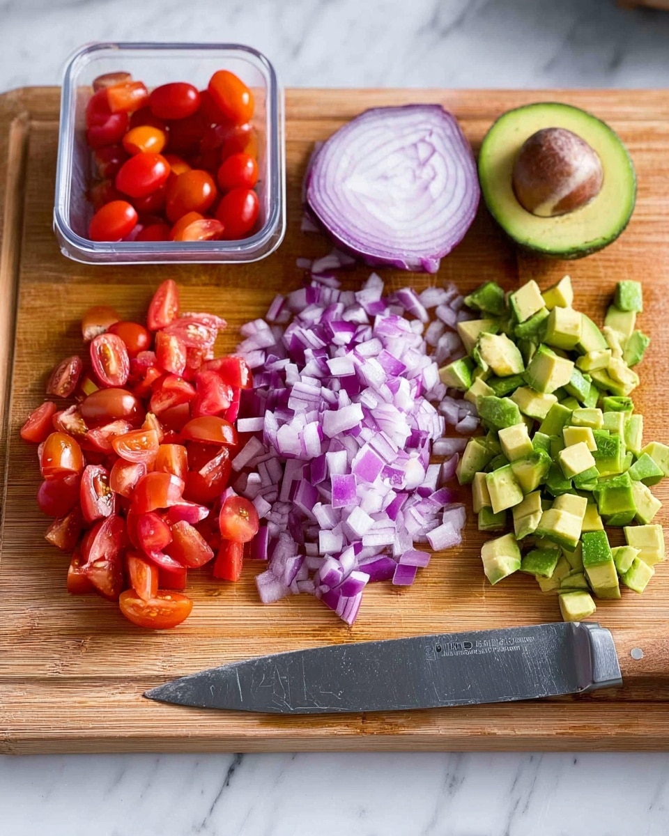 A wooden cutting board is placed on a white marbled surface, holding chopped ingredients arranged in rows from left to right. On the far left, there are small red grape tomatoes, some whole inside a clear plastic container and some chopped into halves and quarters. In the middle, there is a pile of finely chopped red onion with its halved purple-red onion sitting above it. On the right side, there are small green cubes of avocado, with a halved avocado showing its seed just above the chopped pieces. A large kitchen knife with a wooden handle lies along the right edge of the board. The scene is brightly lit, showing clear details and vibrant colors. photo taken with an iphone --ar 4:5 --v 7