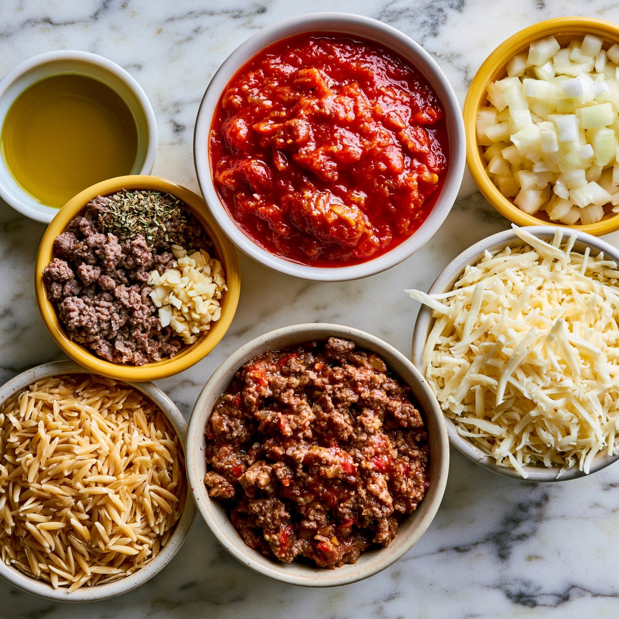 A close-up view of a bowl filled with creamy orange pasta mixed with small ground meat pieces. The pasta has a soft, smooth texture and is coated with sauce that looks thick and rich. Bits of chopped green herbs are scattered on top, adding bright color contrast. The bowl is white with a speckled rim and sits on a white marbled surface. A spoon rests in the bowl, partially visible on the right side. photo taken with an iphone --ar 4:5 --v 7